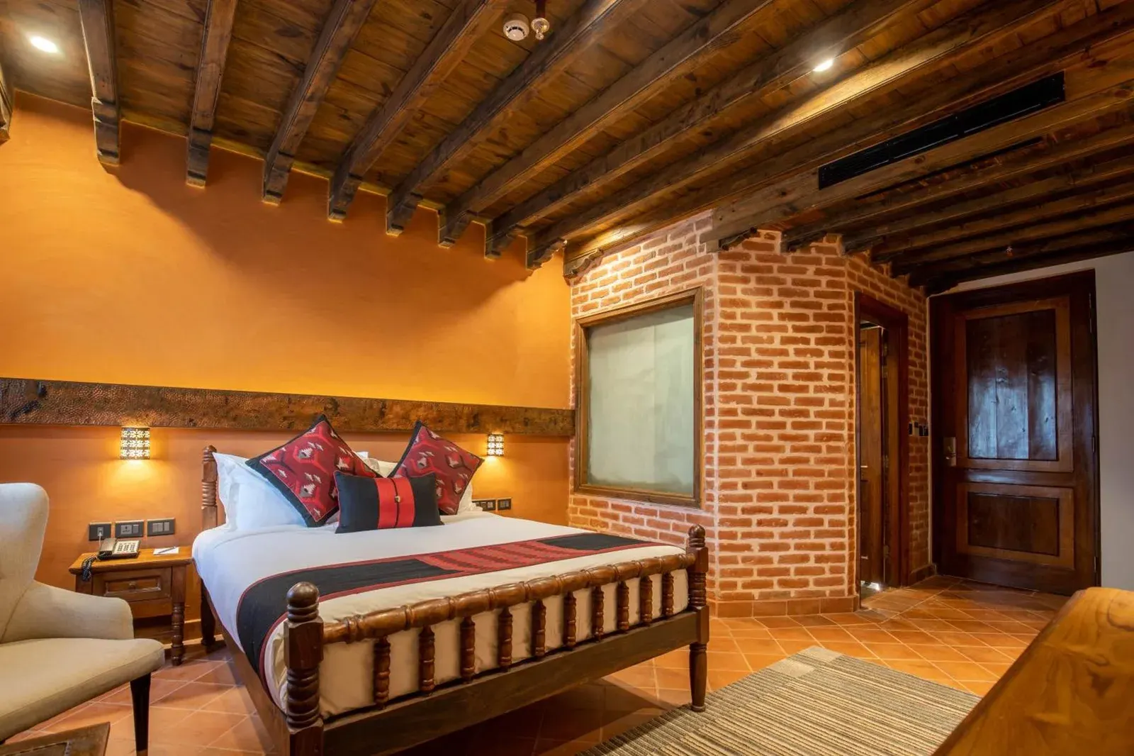 Una habitación king en Basera Boutique Hotel - La escapada oculta de Kathmandu, con una cama de madera tallada y un interior de ladrillo y yeso.