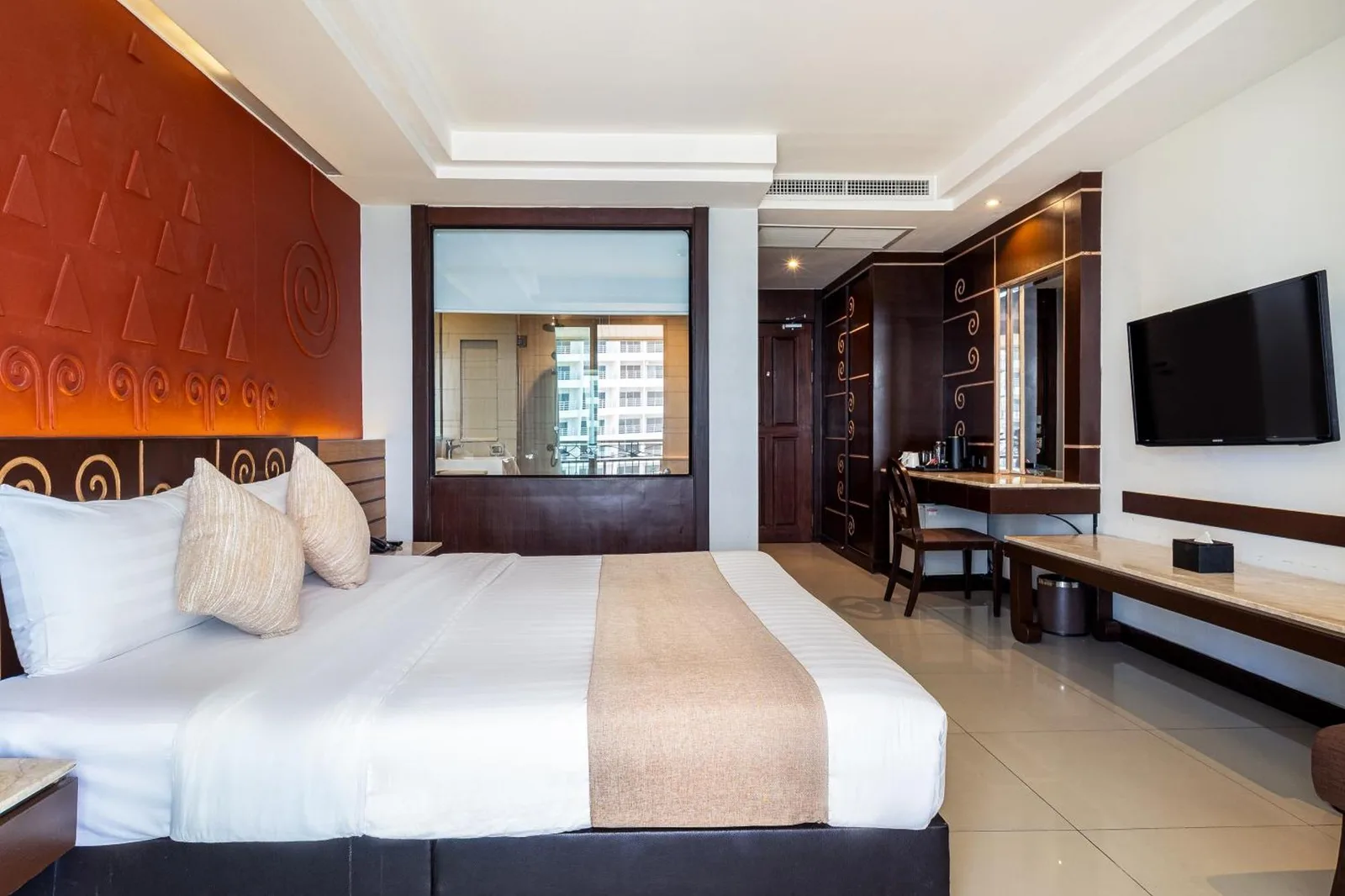 Amplia habitación de huéspedes en Bay Beach Resort Jomtien en Pattaya con cama, TV y escritorio de trabajo