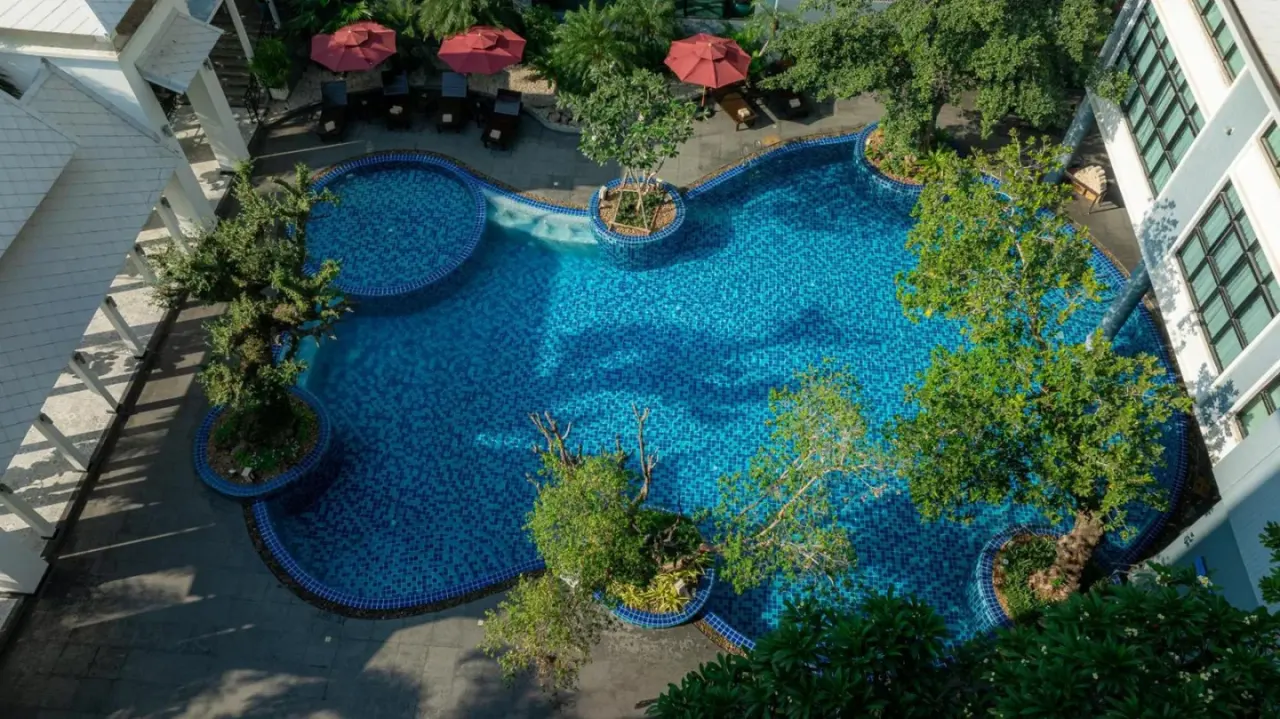 Zona de la piscina en Bay Beach Resort Jomtien en Pattaya con piscina de mosaico azul y sombrillas
