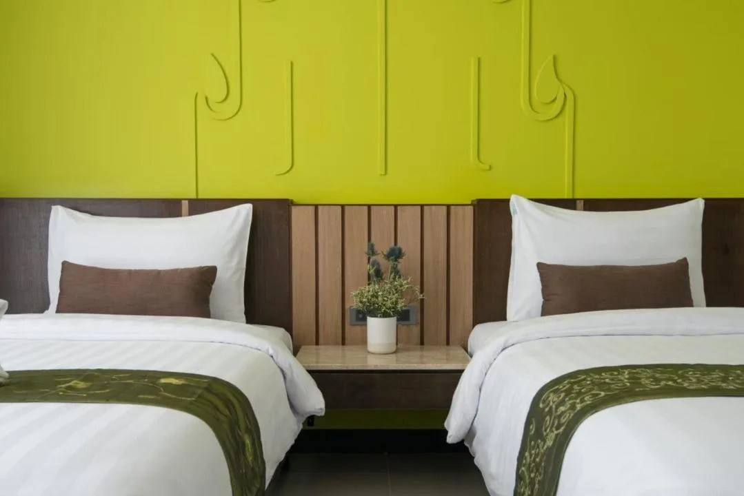 Camas twin con pared de acento verde en una habitación de Bay Beach Resort Jomtien en Pattaya