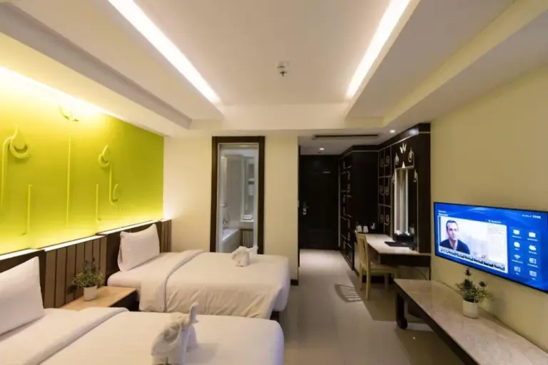 Habitación Twin en Bay Beach Resort Jomtien en Pattaya con interior luminoso y cortinas del balcón