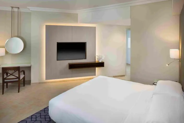 Beach Rotana – All Suites – ein Schlafzimmer mit einem weißen Bett und einem TV im Beach Rotana – All Suites in Abu Dhabi