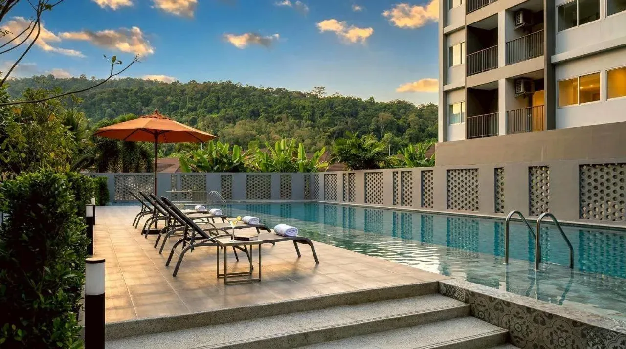 Pool terrace at Beehive Boutique Hotel Phuket in Phuket with sun loungers, umbrella, and mountain views
