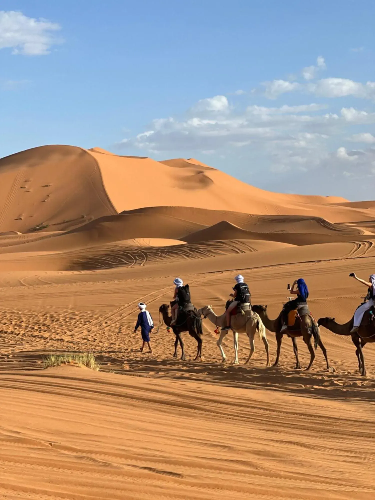 Caravane de chameaux dans le Sahara près de Berber Spirit Luxury Camp à Merzouga avec des cavaliers traversant les dunes de sable.