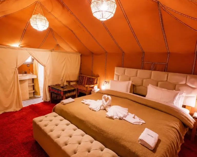 Hébergement sous tente partagé au Berber Spirit Luxury Camp à Merzouga avec plusieurs lits et une décoration à motifs.