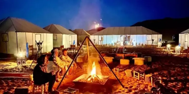 Best Classic Sahara Experiences in Merzouga campfire lounge with guests sitting around a fire at night
