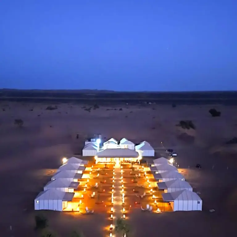 Best Classic Sahara Experiences in Merzouga desert camp exterior at dusk with illuminated tents in the Sahara