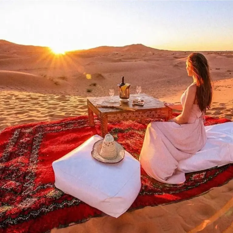 Best Classic Sahara Experiences in Merzouga sunset dining setup on the dunes with cushions and a table