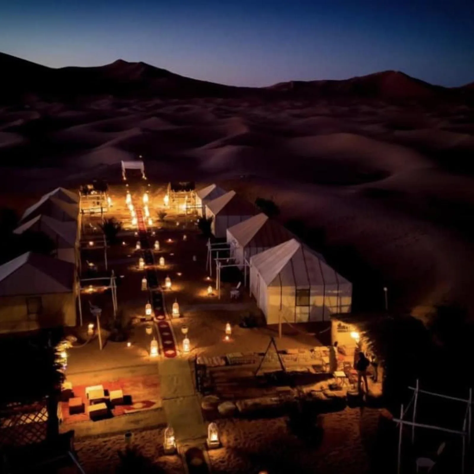 Aerial view of Bikhir Luxury Camp in Merzouga at dusk surrounded by desert dunes