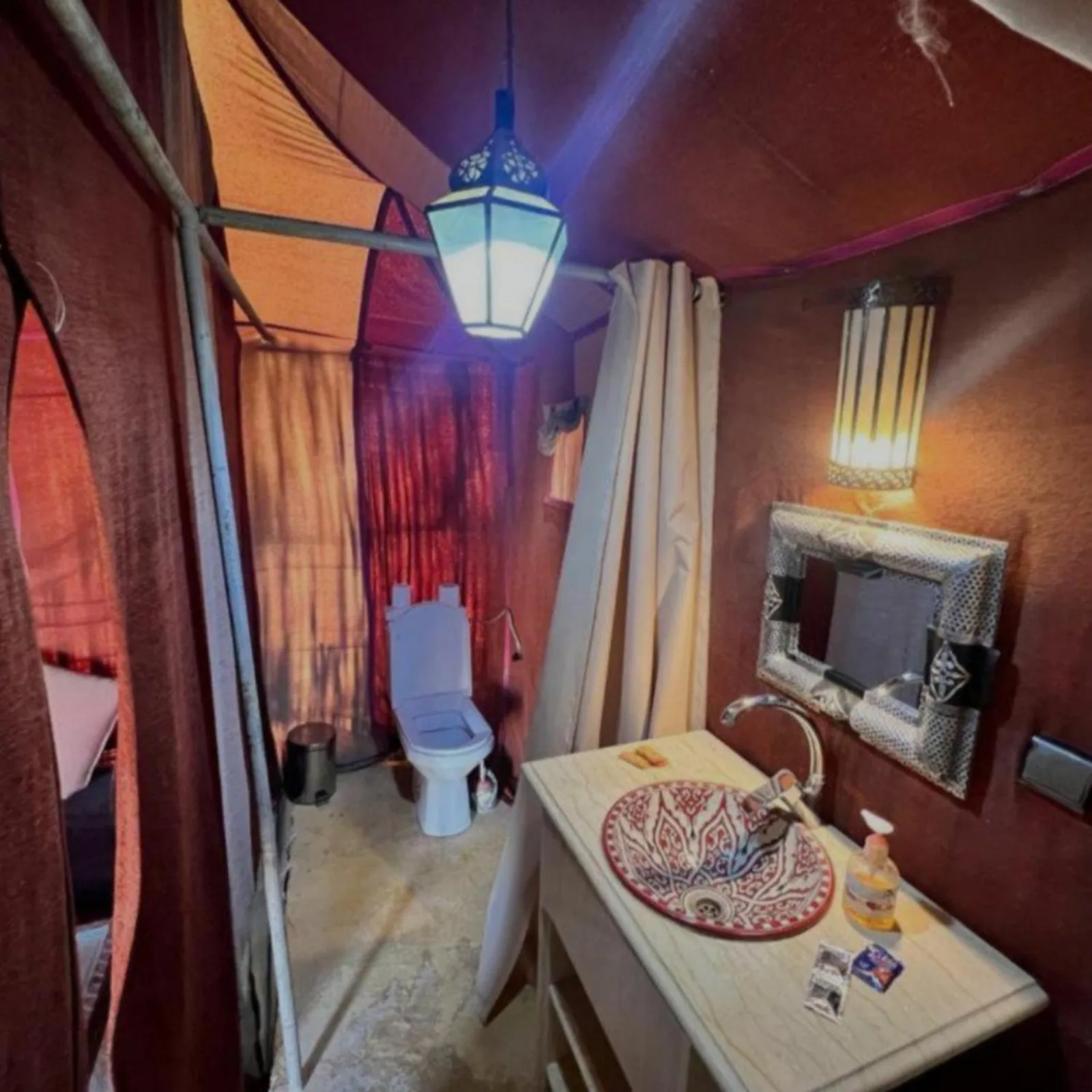 Bathroom interior at Bikhir Luxury Camp in Merzouga with sink, toilet, and shower curtain