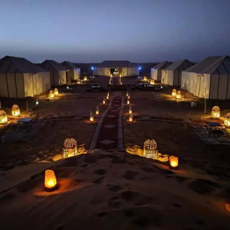 Bikhir Luxury Camp in Merzouga illuminated at night with lanterns and tents in the desert