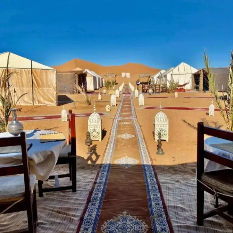 Outdoor dining walkway at Bikhir Luxury Camp in Merzouga with lanterns and tents