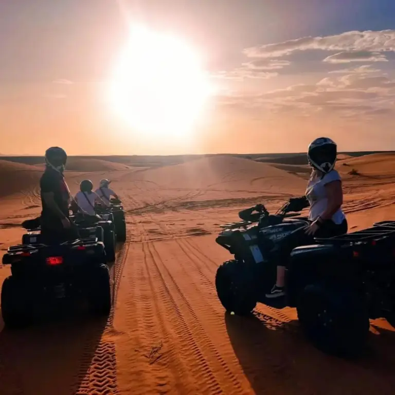 Guests on quad bikes in the desert near Bikhir Luxury Camp in Merzouga at sunset