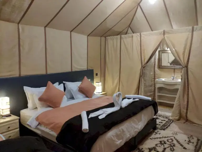 Elegant double suite at Blue Sky Luxury Camp in Merzouga with neutral bedding, canopy-style tent walls, and an en-suite bathroom.