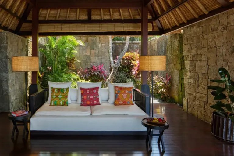 Espace lounge confortable au Bvlgari Resort Bali avec des coussins vibrants et de la verdure