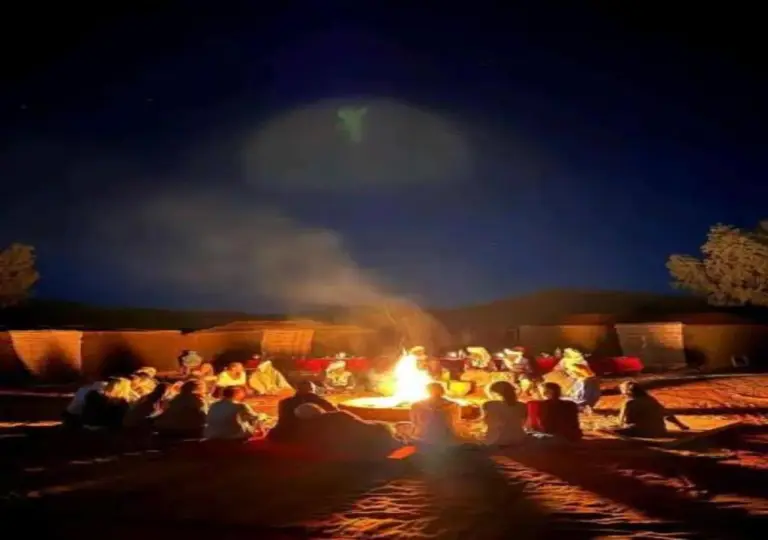 Camel Trekking Desert Camp in Merzouga guests gathered around a campfire at night in the desert