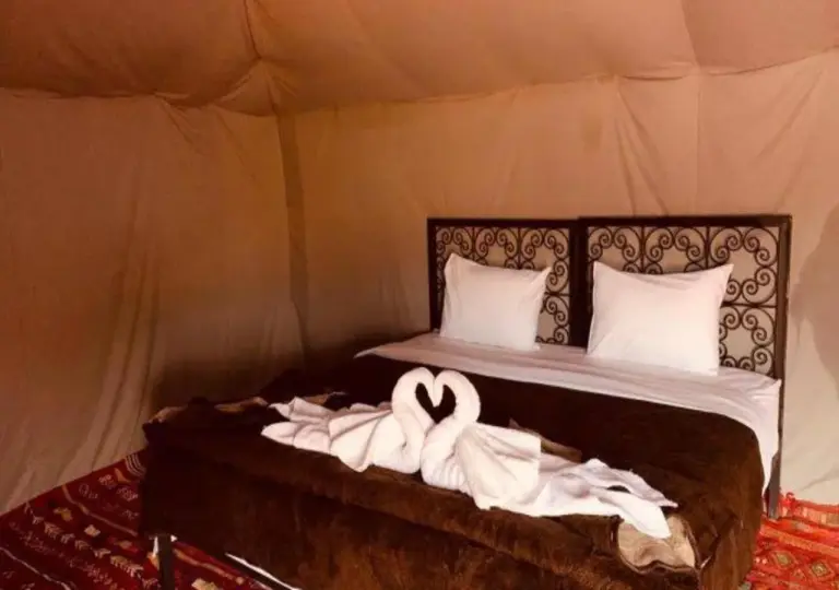 Camel Trekking Desert Camp in Merzouga luxury tent bed with towel swan decoration