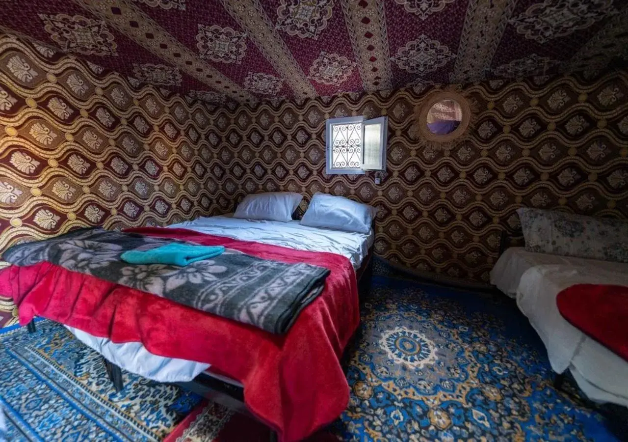 Camel Trekking Desert Camp in Merzouga traditional decorated tent room with beds and patterned carpets