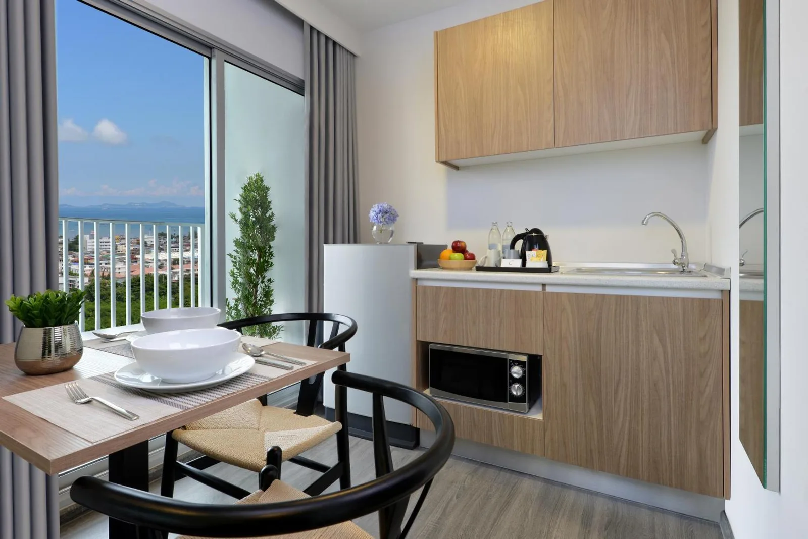 Kitchenette and dining area at Centre Point Prime Hotel Pattaya with balcony and city views