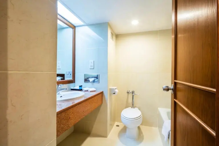 Cholchan Pattaya Beach Resort - SHA Extra Plus Badezimmer mit Waschbecken, Toilette und beigen Fliesen in Pattaya