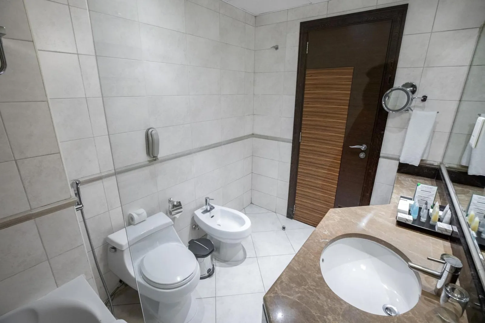 Bathroom in City Premiere Hotel Apartments Dubai with toilet, bidet, sink, and tiled walls.