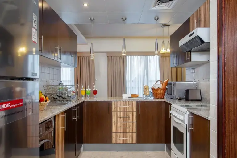 Fully equipped kitchen at City Premiere Hotel Apartments Dubai with stove, refrigerator, washer, and microwave.