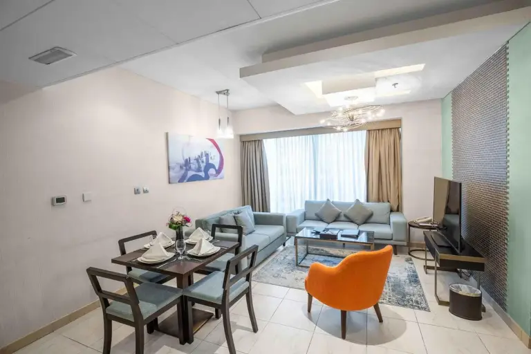 Stylish living room at City Premiere Hotel Apartments Dubai with sofa seating, dining table, and TV.