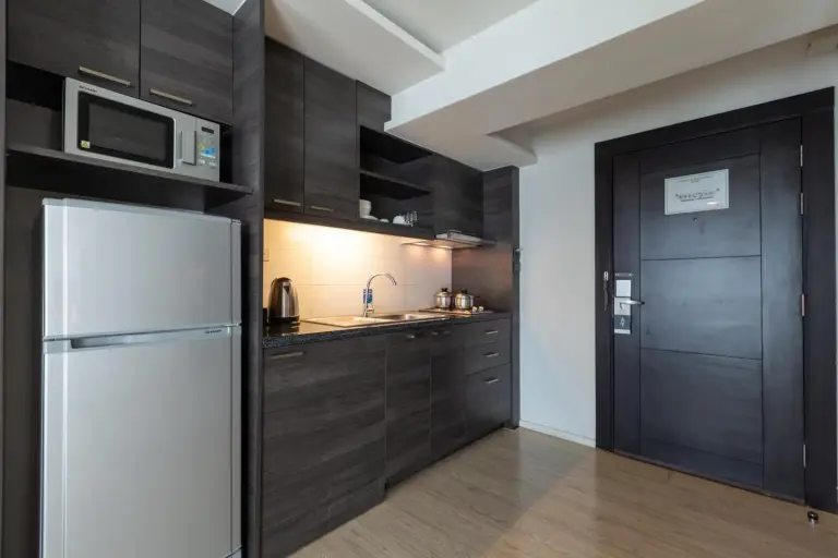 Kitchenette dans Classic Kameo Hotel & Serviced Apartments, Ayutthaya avec réfrigérateur, micro-ondes, évier et placards de rangement.