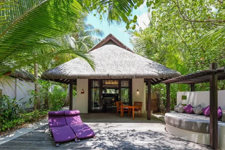 Charming entrance of a villa at Coco Bodu Hithi surrounded by tropical greenery in the Maldives.