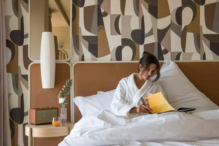 Huésped disfrutando de un libro en la cama en Columbus Urban Resort en Florencia