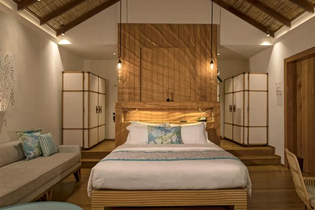 Stylisches Schlafzimmer in einer Villa im Constance Moofushi Maldives mit natürlicher Dekoration.