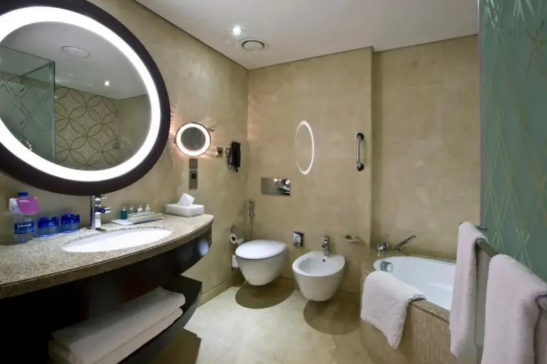 Salle de bains moderne au Crowne Plaza Dubai Deira à Dubai avec meuble vasque, baignoire, toilettes et bidet