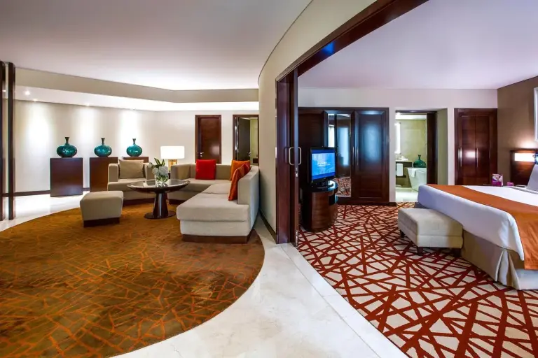 Chambre et espace salon élégants d'une suite à l'hôtel Crowne Plaza Dubai Deira à Dubai