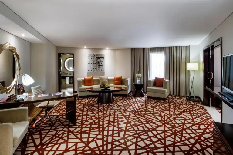 Salon lumineux d'une suite au Crowne Plaza Dubai Deira à Dubai avec moquette à motifs et coin salon