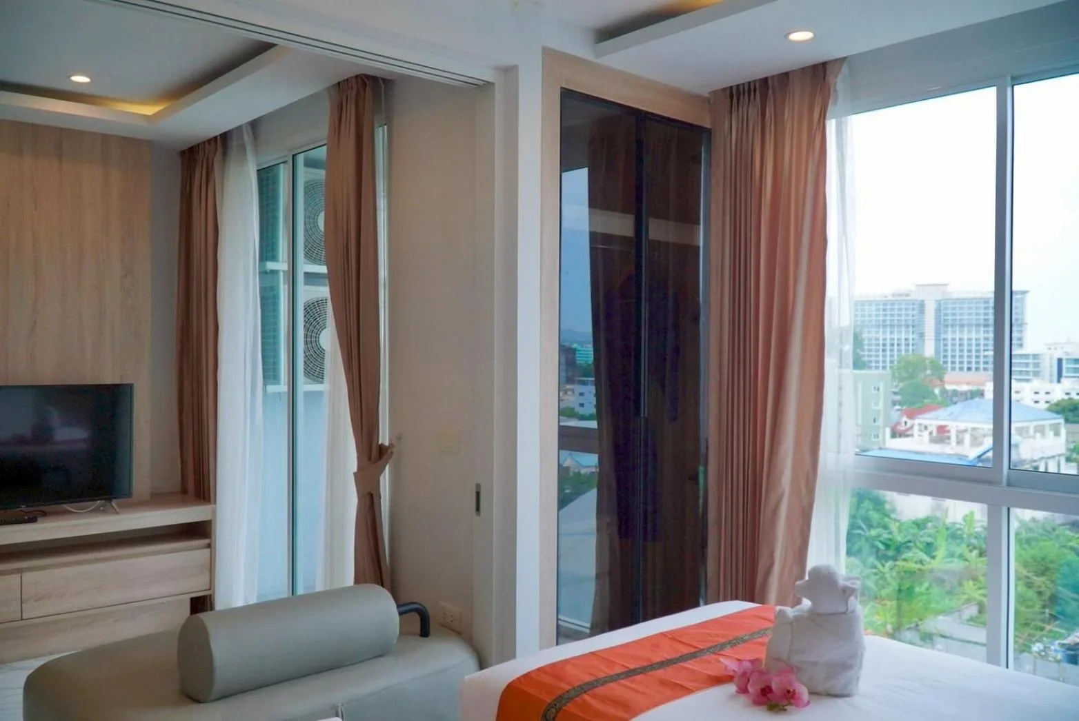 Suite-Schlafzimmer im D Eco Wellness Center Pattaya mit Bett, Sofa, TV-Bereich und Stadtblick