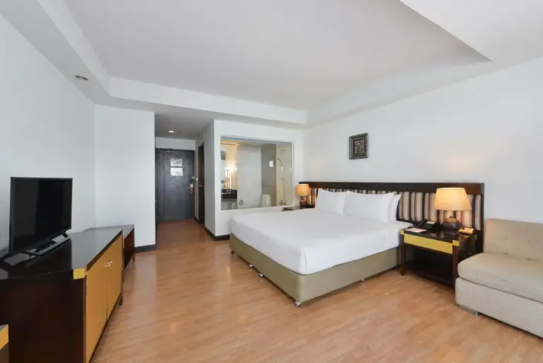 Guest room interior at D Varee Jomtien Beach, Pattaya with bed, desk, wardrobe, and kitchenette area.