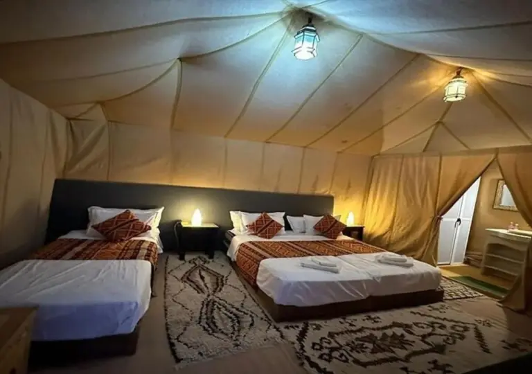 Desert Aura Luxury Camp in Merzouga triple room with three beds and patterned bedding inside a luxury tent