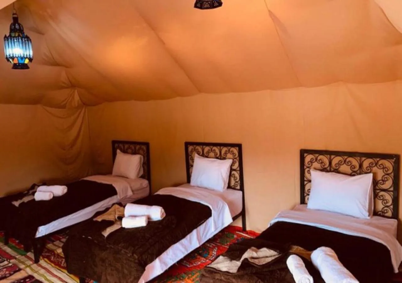 Desert Aura Luxury Camp in Merzouga triple tent room with three single beds and traditional desert camp decor