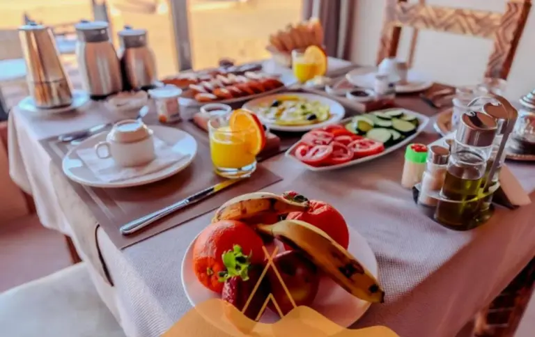 Desert Berber Luxury Camp in Merzouga breakfast table with fruit juice, tea, and fresh food
