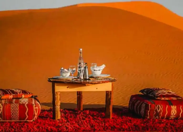 Desert Berber Luxury Camp in Merzouga outdoor dining setup with tea service beside the dunes