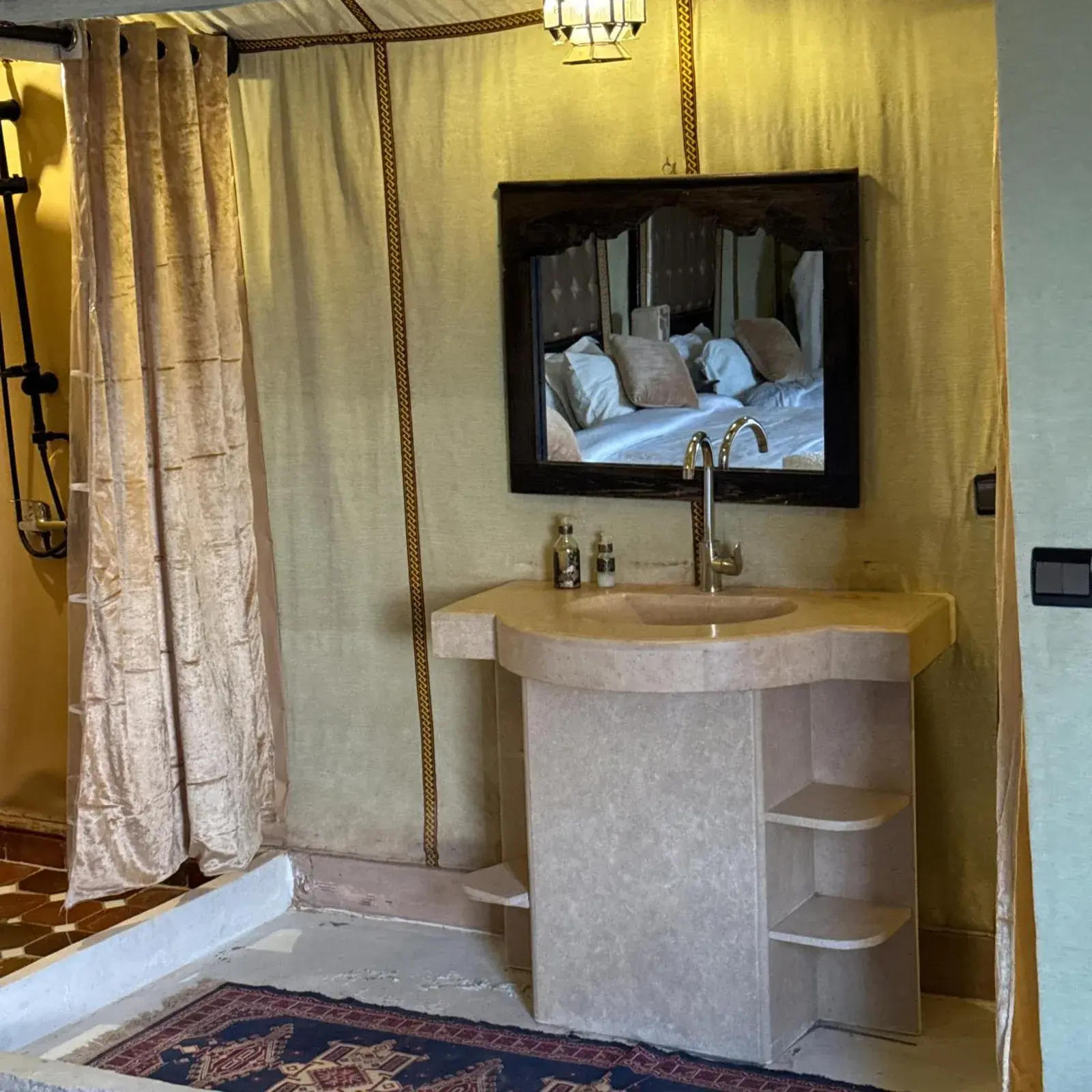 Desert camp merzouga – Merzouga, Morocco hotel – a bathroom with a sink and a bed in a mirror at Desert camp merzouga in Merzouga