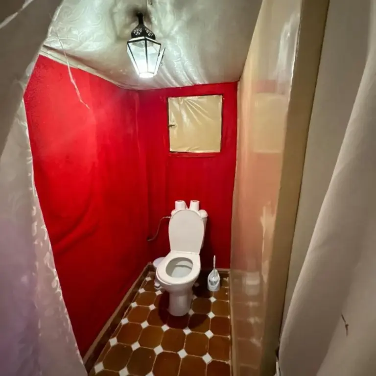 Desert camp merzouga – Merzouga, Morocco hotel – a small bathroom with a toilet in a red room at Desert camp merzouga in Merzouga