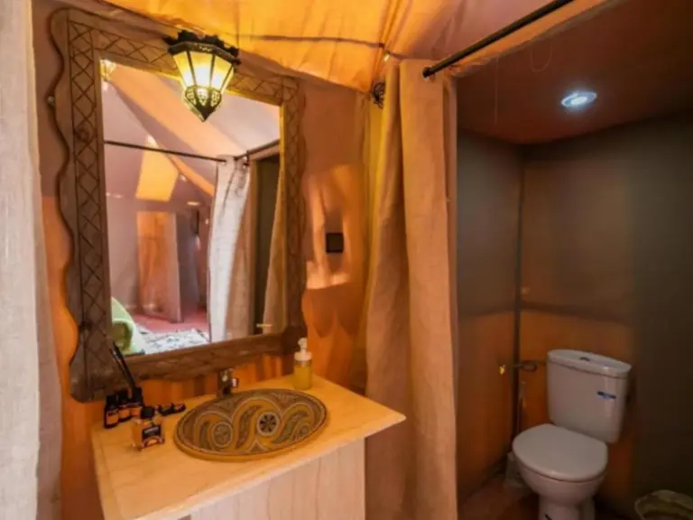 Badezimmer im Desert Paradise Luxury Camp in Merzouga mit Waschtisch, Spiegel und separatem Toilettenbereich