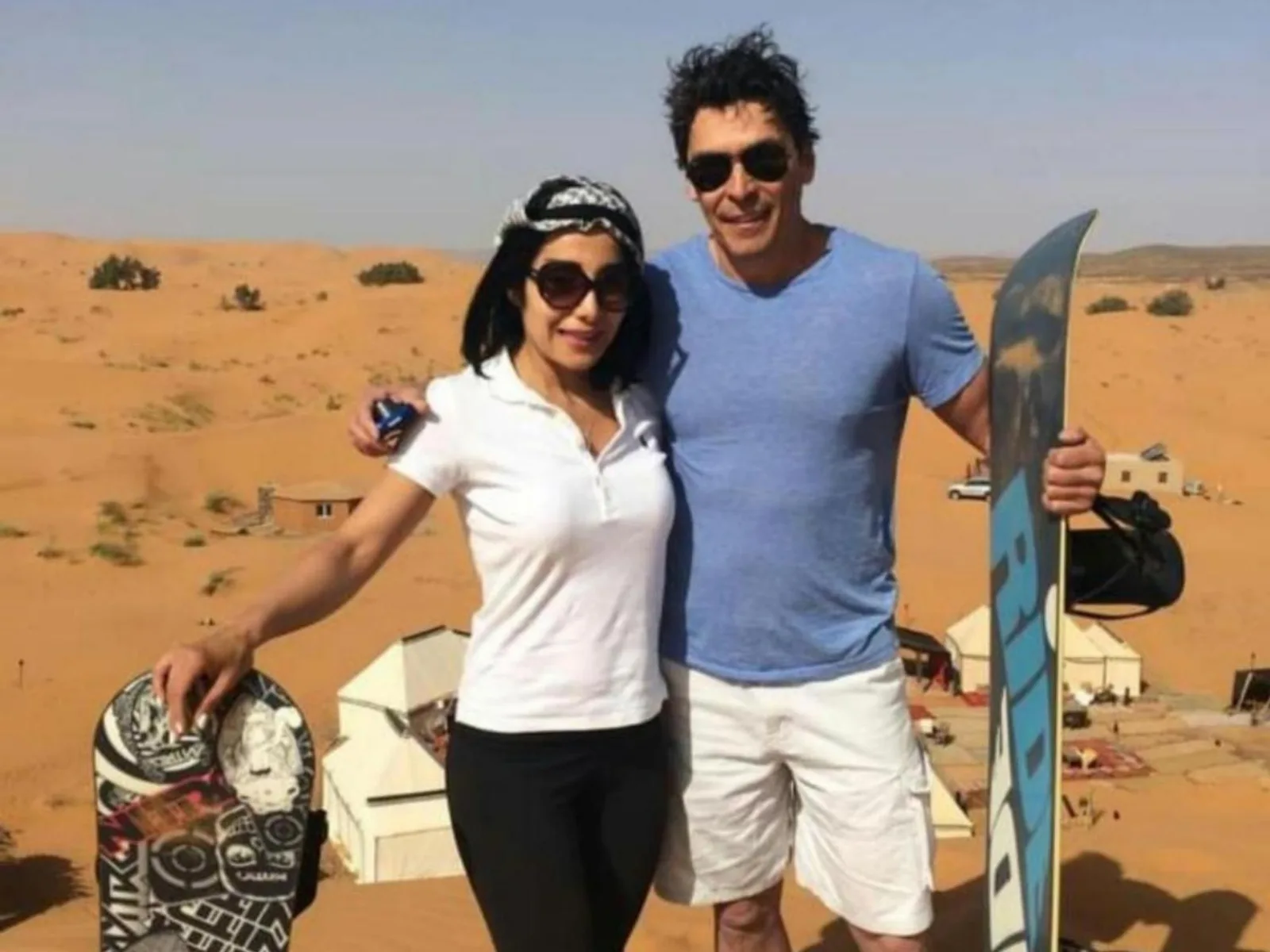 Gäste posieren im Desert Paradise Luxury Camp in Merzouga mit Sandboards und Wüstenzelten im Hintergrund