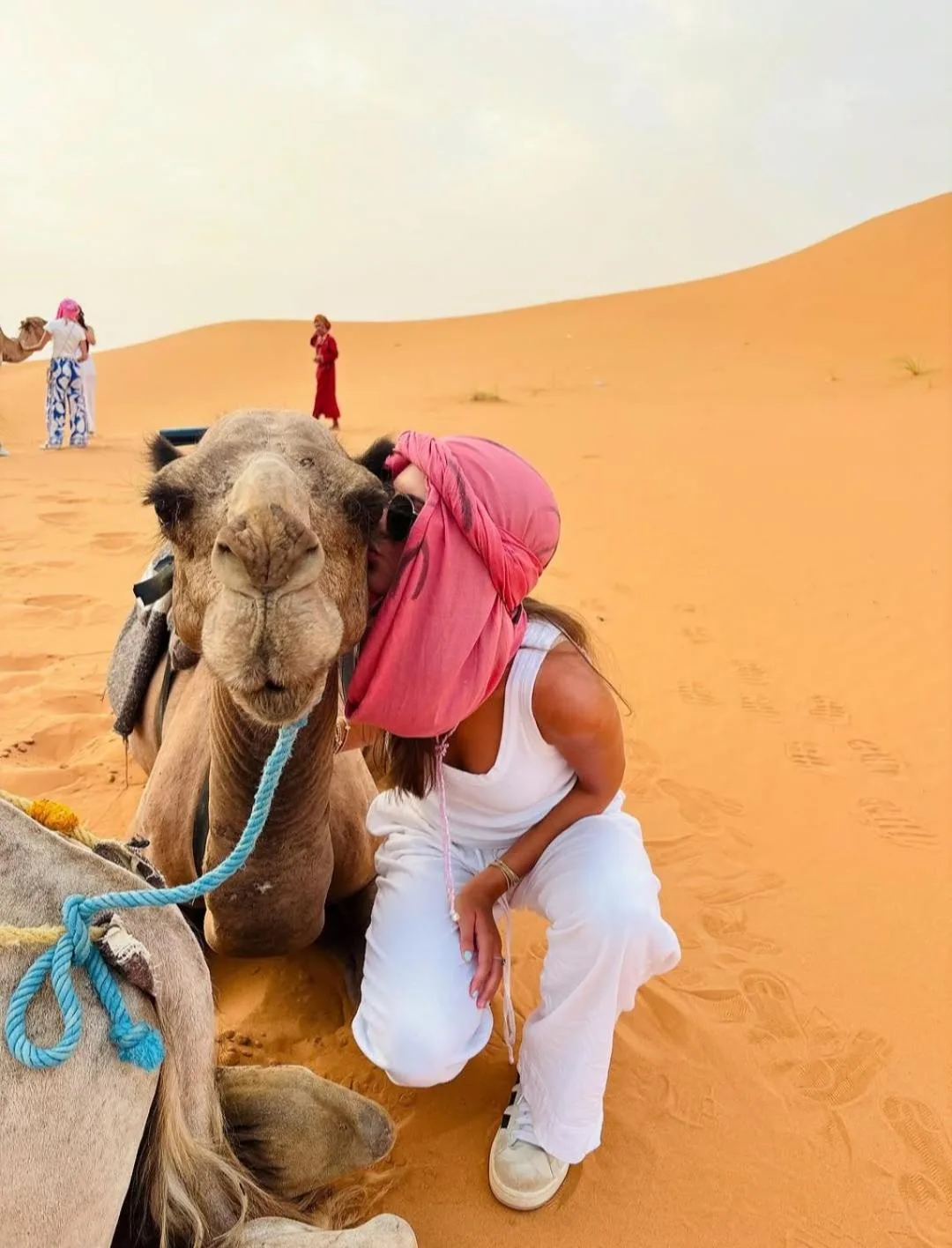Gast posiert mit einem Kamel nahe dem Desert Pearl Camp Merzouga in Merzouga in der Wüste