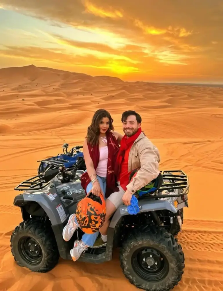 Paar fährt bei Sonnenuntergang in der Wüste auf einem Quadbike im Desert Pearl Camp Merzouga in Merzouga