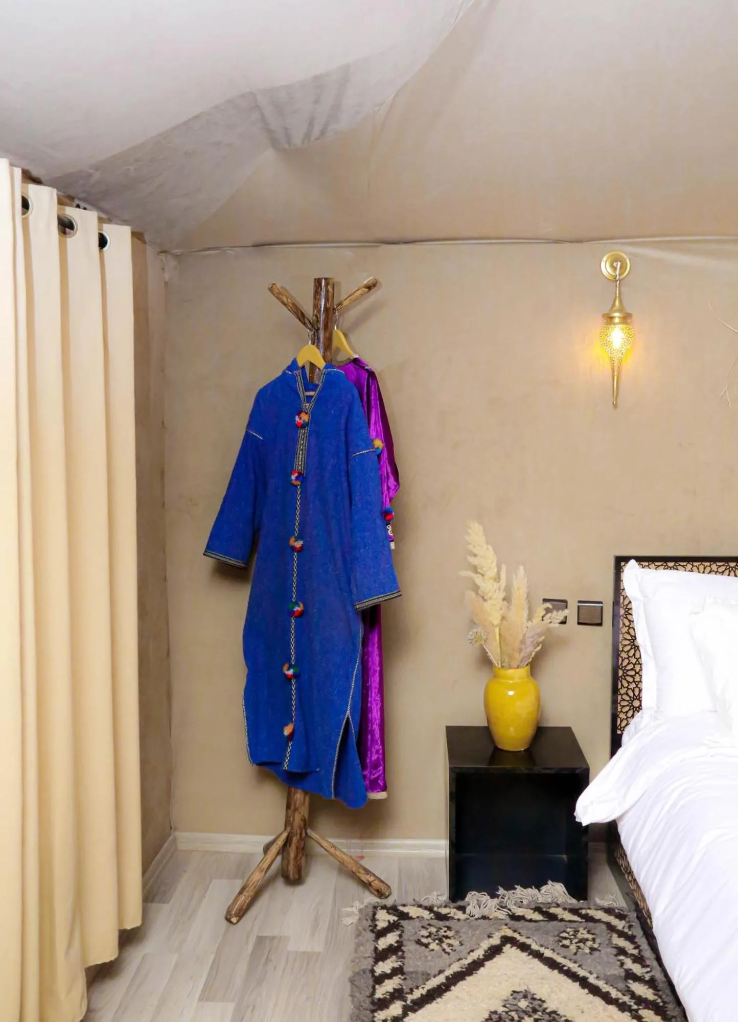 Im Inneren eines Zelts im Desert Pearl Camp Merzouga in Merzouga mit Kleiderständer, Nachttisch und Bett