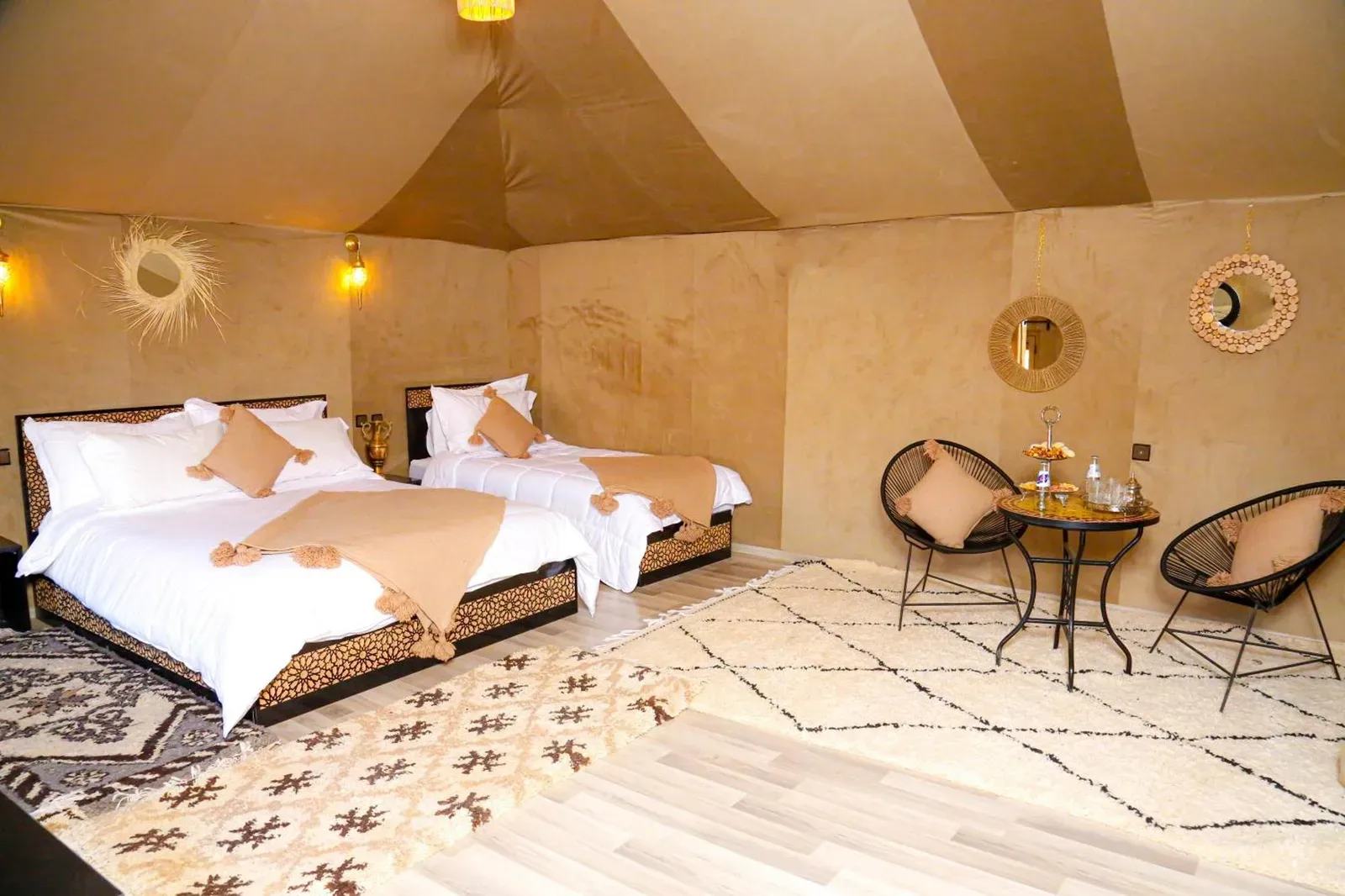 Zelt-Suite mit zwei Betten im Desert Pearl Camp Merzouga in Merzouga mit marokkanischer Einrichtung und Sitzbereich