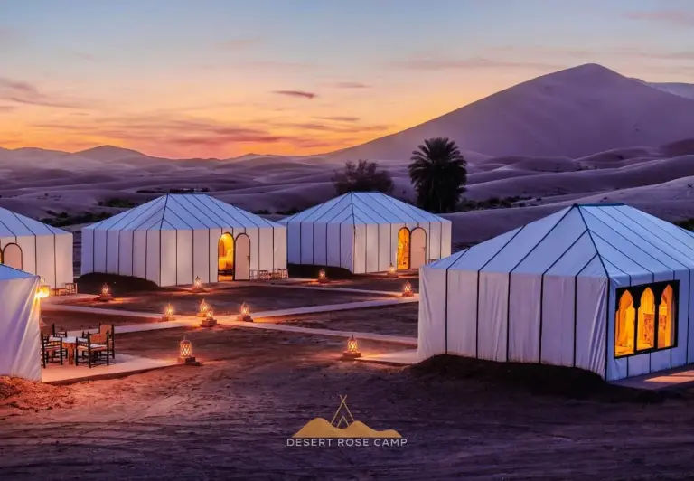 Extérieur d’un campement de tentes de luxe au Desert Rose Camp à Merzouga avec les dunes du désert au lever du soleil