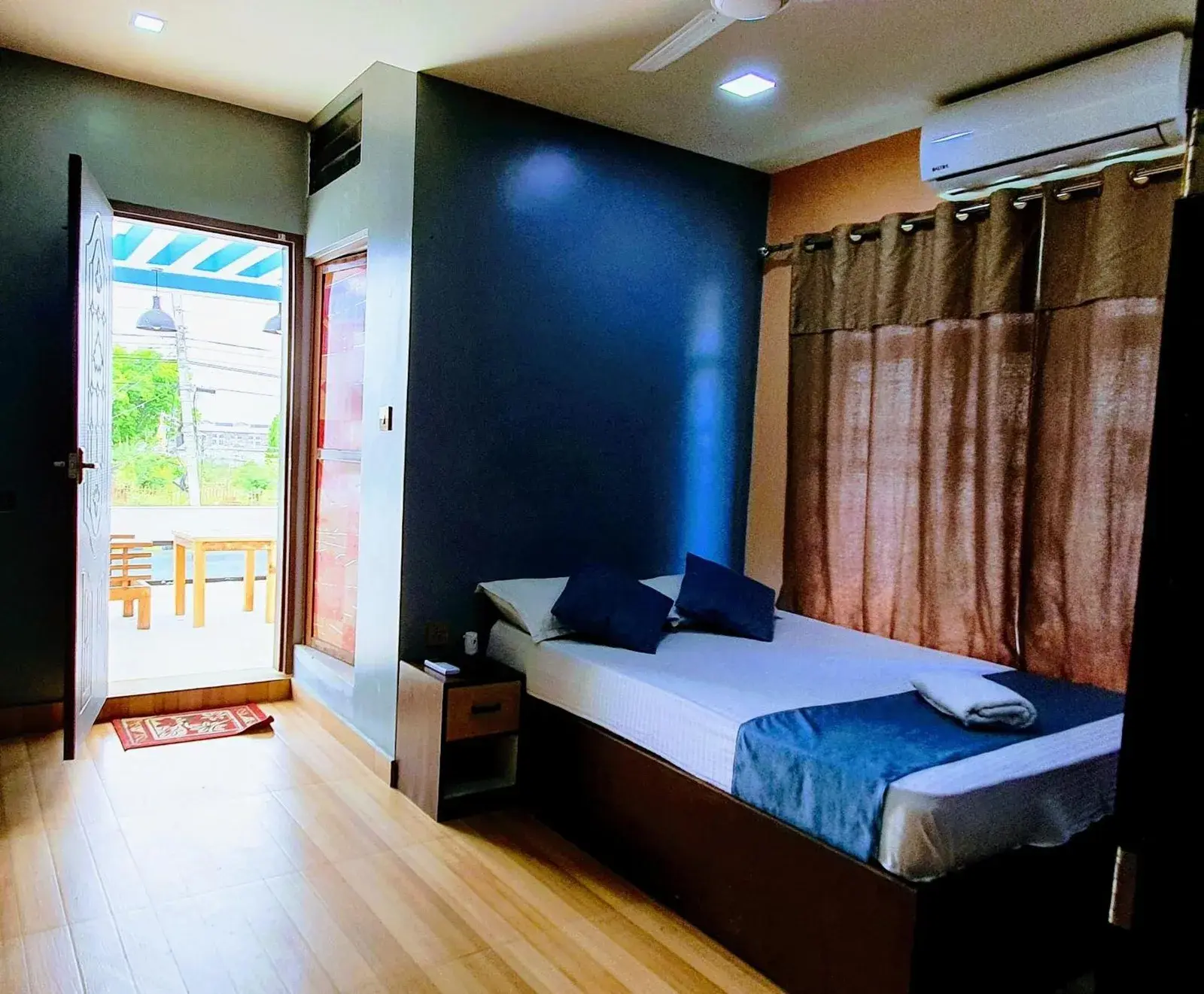 Una acogedora habitación de huéspedes en Devtara Himalayan Hotel en Lumbini con una cama individual, aire acondicionado y acceso al balcón